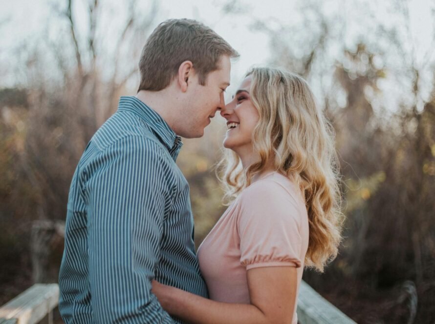 a man and woman smiling and touching noses