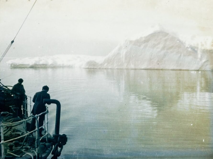 Two men near large iceberg