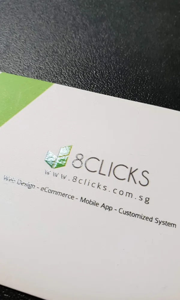 8Clicks | A Close-Up Of A Business Card Featuring The 8Clicks Logo And Website. Text Below The Logo Highlights Services Including Web Design, Ecommerce, Mobile App Development, And Customized Systems. The Card Has A Contrasting Color Scheme With A Hint Of Green In The Corner.